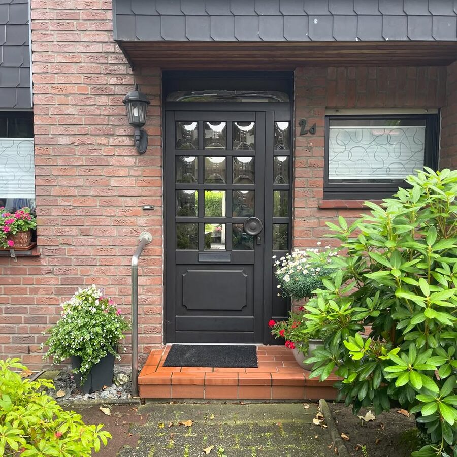 Schwarze Haustür mit Glaselementen an einem Backsteinhaus