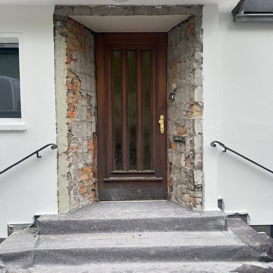 Holz-Haustür mit Seitenteilen am Treppeneingang eines Wohnhauses