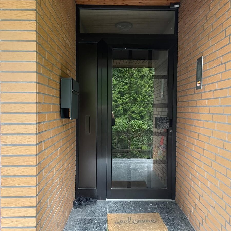 Moderne graue Haustür in einer Klinker-Eingangsnische